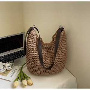 Détail du sac en paille tressée avec poignées en cuir et doublure sur bureau blanc