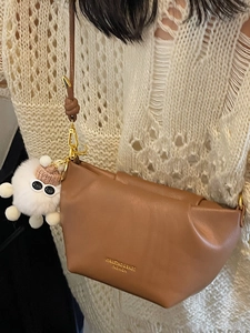Brown leather dumpling crossbody bag for women with cute white plush ball pendant detail