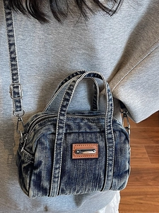 Distressed denim top-handle bag in washed blue with adjustable shoulder strap for women