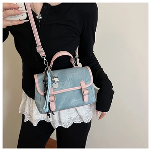Detail of blue tote bag with pink trim, metal star charm, and adjustable strap