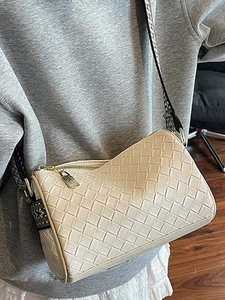 Chic cream woven crossbody pillow bag with wide patterned strap and gold zipper detail