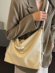 Sac fourre-tout beige en similicuir avec perles et chaîne dorée sur un mannequin