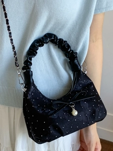 Fashionable black quilted bucket bag with pearl bow detail and stylish chain strap
