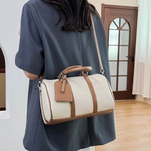 Close-up of cream and tan leather Boston bag with silver hardware on a model