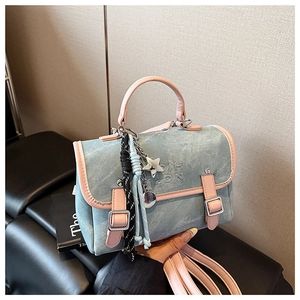 Detail view of denim texture, pink leather trim, and charms on women's backpack