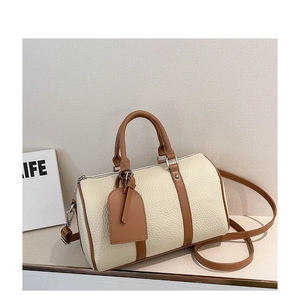 Detail view of cream white litchi grain leather bag with brown trim and shoulder strap