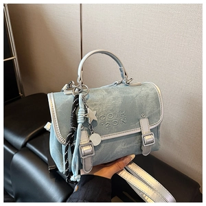 Detail view of light blue denim handbag with silver trim, logo, and star charms
