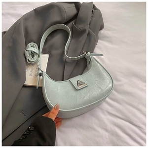 Detailed shot of mint green crescent bag with glossy texture and silver buckle