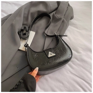 Detail of black crescent bag featuring wrinkled oil-wax texture and metal buckle