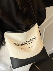 Minimalist canvas tote bag with black leather trim and crossbody strap for women