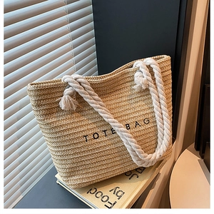 Detail of hand-woven straw tote bag with cotton rope handles and black text print