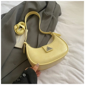 Detail of light yellow crescent bag with pleated texture and triangle metal clasp