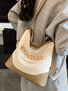Large beige canvas and brown leather tote bag with shoulder strap for summer style