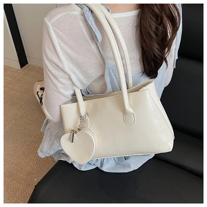 Detailed view of cream white tote bag with long straps and heart coin purse pendant