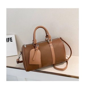 Close-up of brown litchi grain leather Boston bag with double handles and hardware details