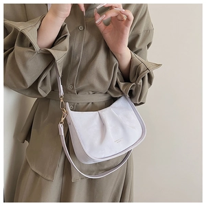 Détail du sac demi-lune plissé lavande avec fermoir doré porté sur un manteau