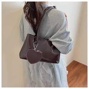 Close-up of a chocolate brown glossy leather shoulder bag with a heart zipper pendant