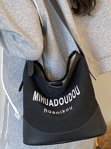 Chic black canvas tote bag with leather base and white lettering for casual daily use