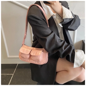 Side view of pink patent leather shoulder bag with double flap pockets on a model