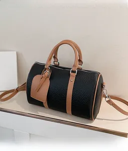 Close-up of black lychee grain leather Boston bag with caramel brown handles and silver zipper