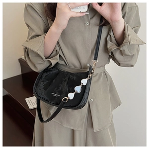 Détail du sac bandoulière noir mat avec breloque cœur bleu et fermeture éclair