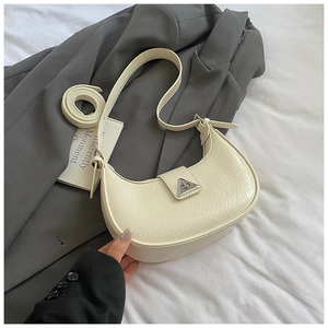 Close-up of beige crescent moon bag featuring wrinkled leather texture and metal buckle
