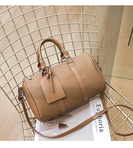 Detailed view of brown lychee texture leather Boston bag with silver hardware on a chair