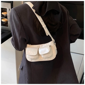 Model wearing a cream white crossbody bag with double front flap pockets and silver hardware