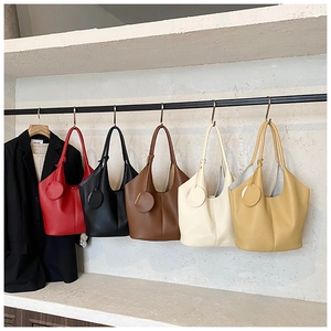 Detail of minimalist tote bags in diverse colors hanging against a textured wall