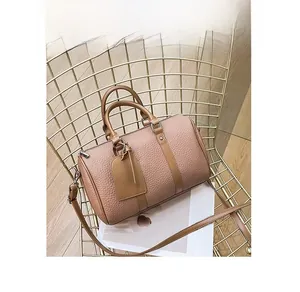 Detail view of pink leather Boston bag with brown handles on a gold metal chair