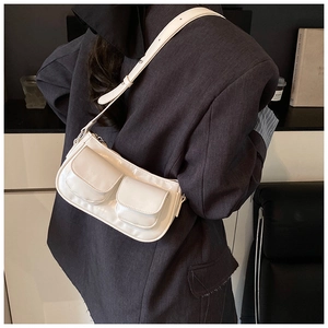 Rear view of a model wearing a white glossy leather shoulder bag with double front pockets