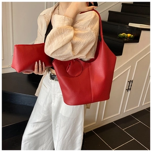 Close-up of red lychee textured tote bag and matching pouch on a fashion model