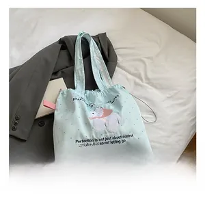 Detail of light blue polka dot canvas tote bag featuring cute cartoon bear embroidery