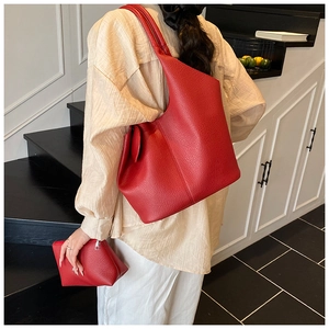 Red pebbled leather hobo tote set with matching pouch shown on a model in minimalist setting