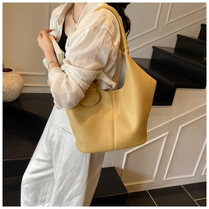 Side view of large yellow leather tote bag showing grainy texture and small coin pouch