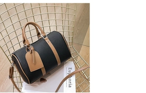 Close-up of contrast color Boston bag featuring black lychee pattern leather and brown handles