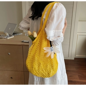 Detail einer gelben gewebten Strandtasche mit Gänseblümchen-Anhänger und Innentasche