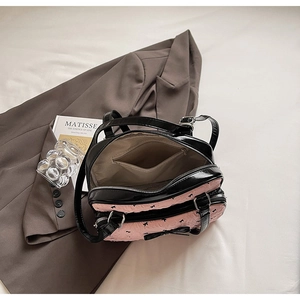 Detail of pink bow-embossed bag featuring double zippers and glossy black leather accents