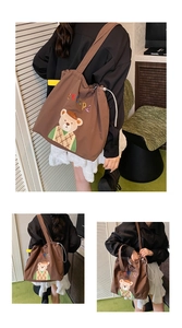 Detailed close-up of brown drawstring tote bag with embroidered bear and colorful letters