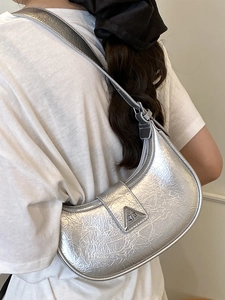 Silver metallic pleated crescent hobo bag with a triangle buckle shown on shoulder