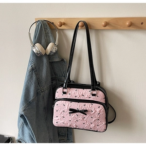 Detail of pink pleated tote bag with bow prints and silver hardware in lifestyle setting