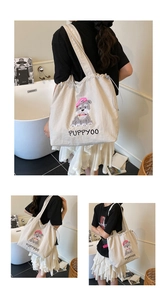 Detail of off-white canvas tote bag with puppy embroidery and functional drawstring closure