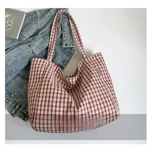 Détail du sac cabas en toile à carreaux rouges et blancs montrant la texture et l'étiquette