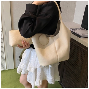 Detail view of cream pebble leather tote and matching pouch set with round charm