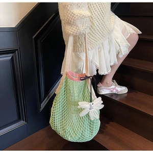 Detaillierte Nahaufnahme der grünen Netztasche mit rosa Rand und weißem Blumenanhänger