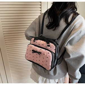 Pink ribbon pattern backpack with black bow details shown on a model's back