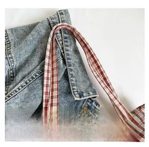 Détail des anses à carreaux rouges et blancs cousues sur le sac fourre-tout en denim