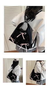 Detail of glossy black faux leather tote with pink ribbon bows and heart metal buckles
