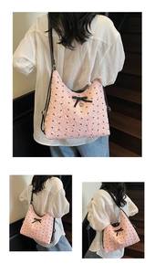 Close-up of pink pleated tote bag with black bow print and heart metal charm detail