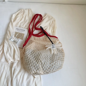 Detail der handgewebten Netztasche mit einer weißen Gänseblume und rotem Kontrastrand